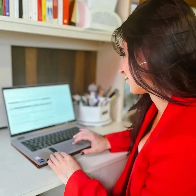 Person raising a hand during a video call with a tutor on a laptop, with an open book nearby