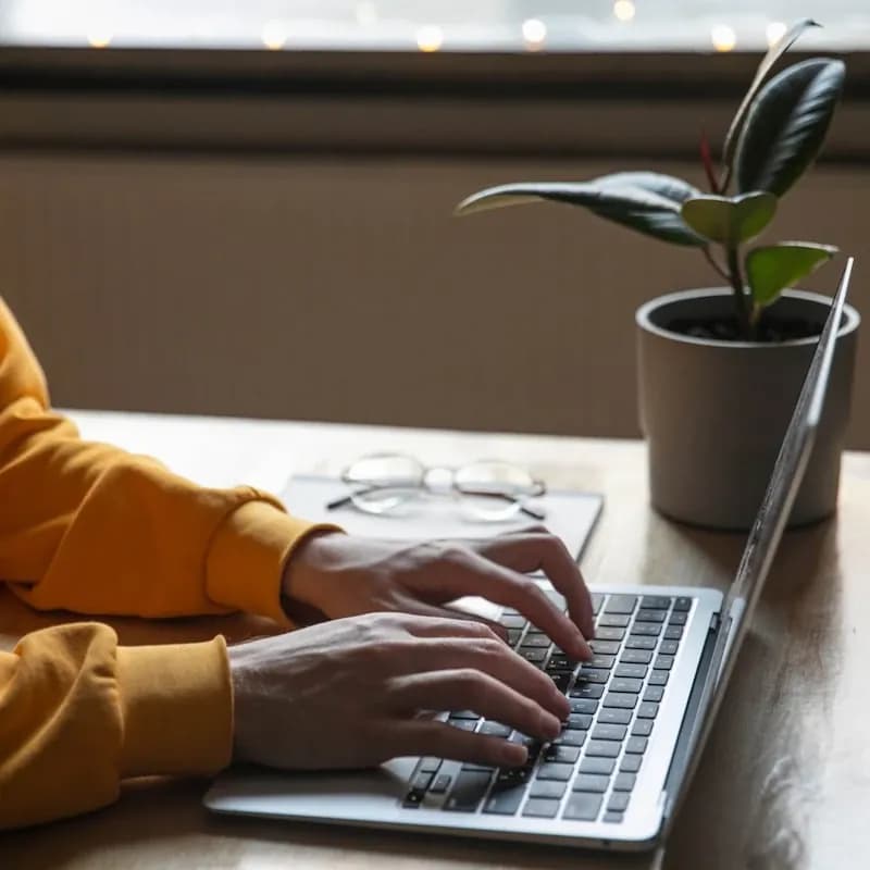 Close-up of hands typing on a laptop keyboard