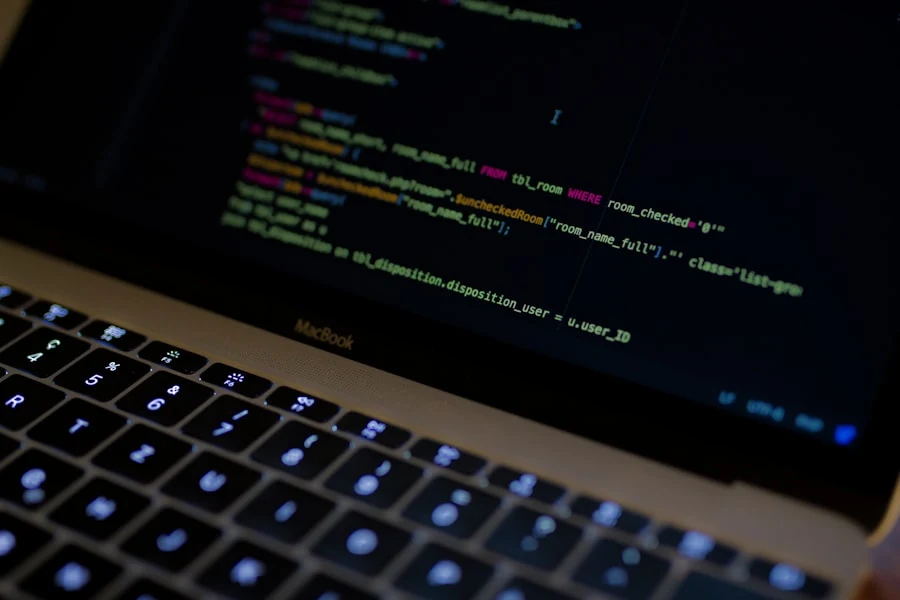 Close-up of a laptop keyboard with code displayed on screen in a dark room