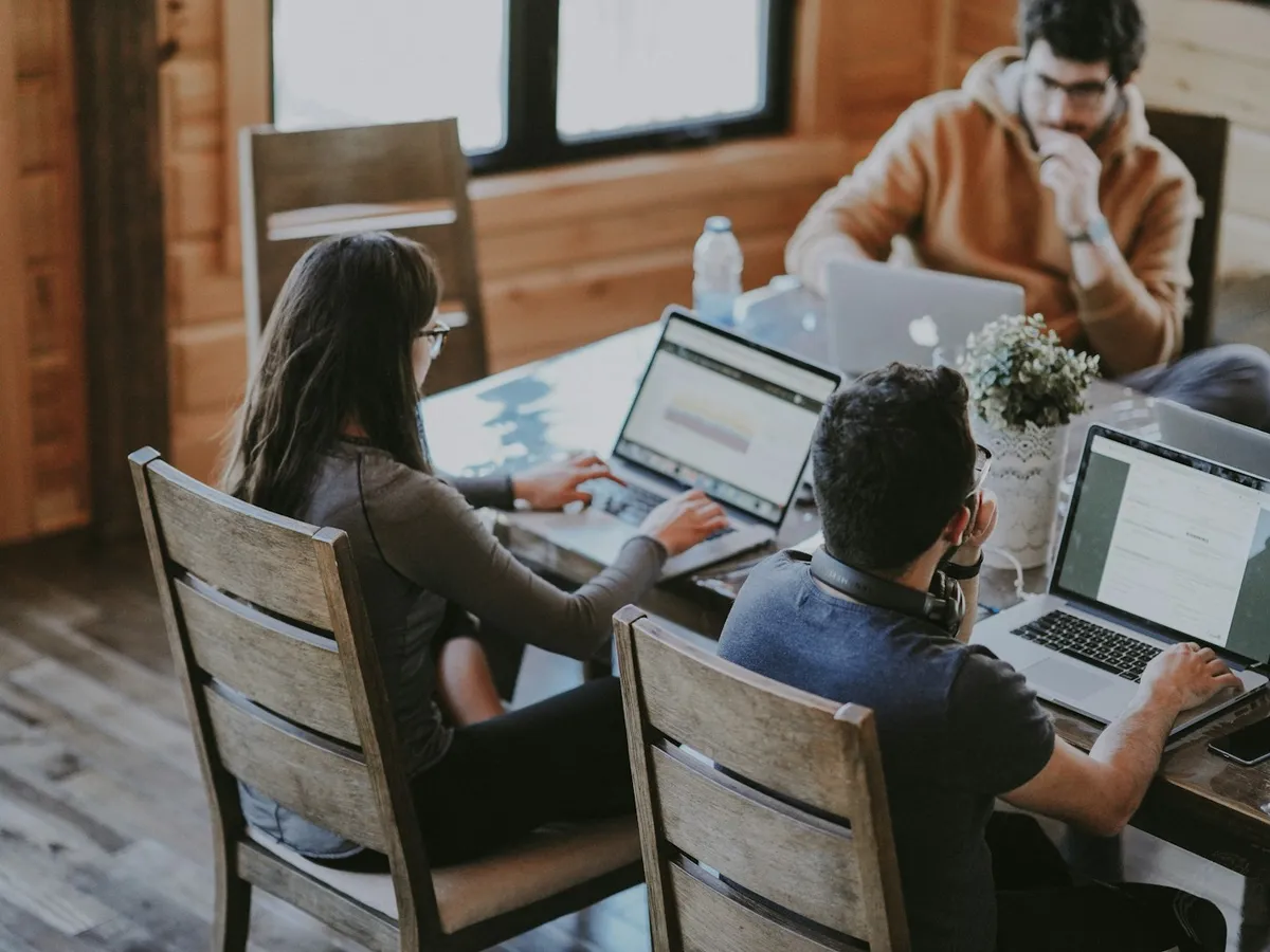Small startup team working together on laptops at a wooden table