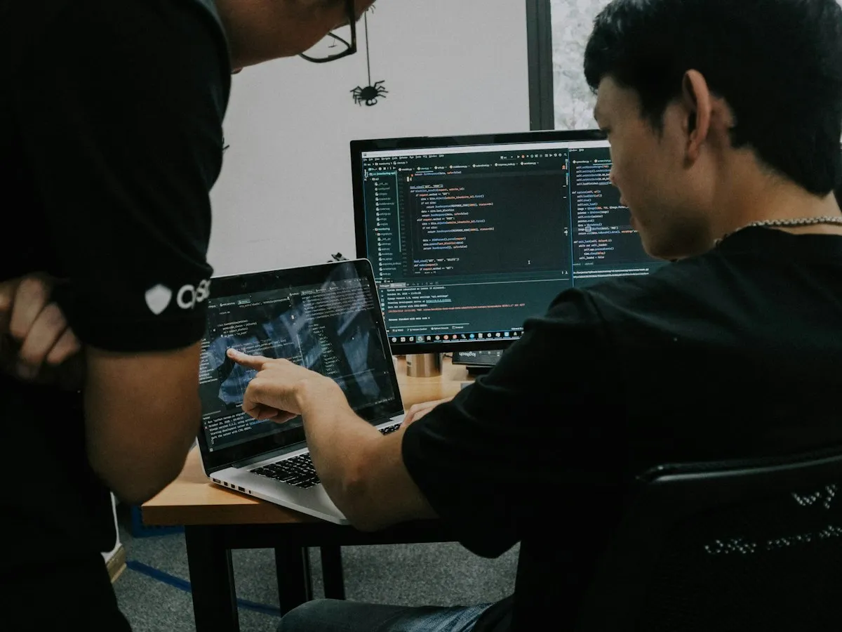 Engineer helping a colleague with code on his laptop